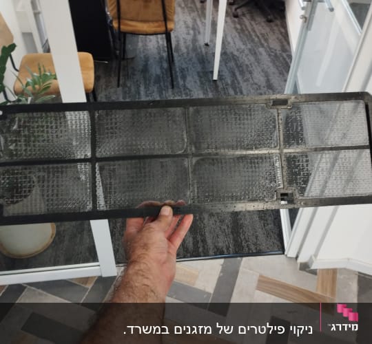 פילטר מזגן מוחזק ביד בתוך משרד